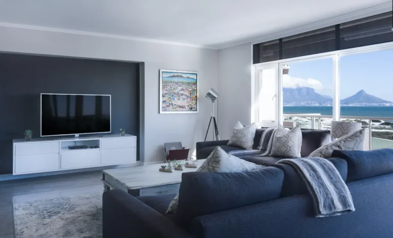 Modern living room interior design with large windows, blue sofa, and coastal view